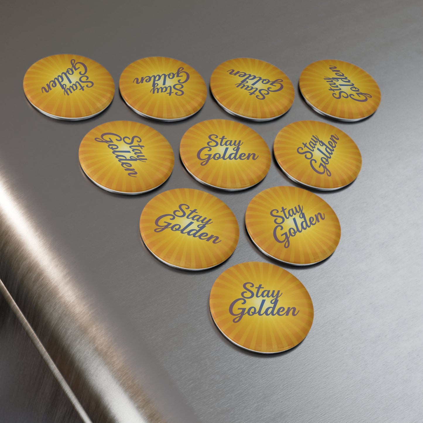 Yellow pins with 'Stay Golden' text on a metallic surface