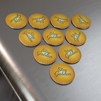 Yellow pins with 'Stay Golden' text on a metallic surface
